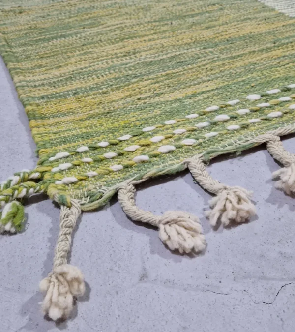Detailed View of Zuri handmade Kilim flatweave rug with a minimalist textured design and geometric shapes on a green background