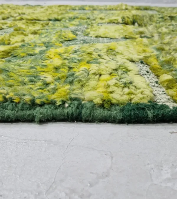 zoomed in view of Hand-knotted Moroccan rug with sculpted high-pile texture, variegated green tones, and dual-pattern design with tassels