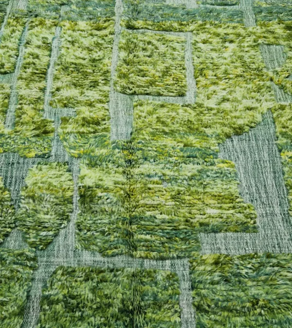 detailed view of Hand-knotted Moroccan rug with sculpted high-pile texture, variegated green tones, and dual-pattern design with tassels