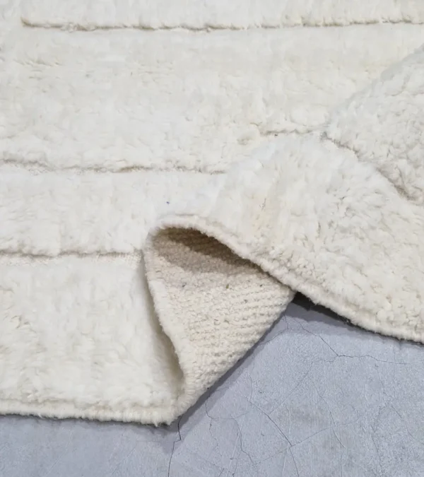 detailed view of Handcrafted ivory Moroccan rug with sculpted high-low grid design and fringe tassels