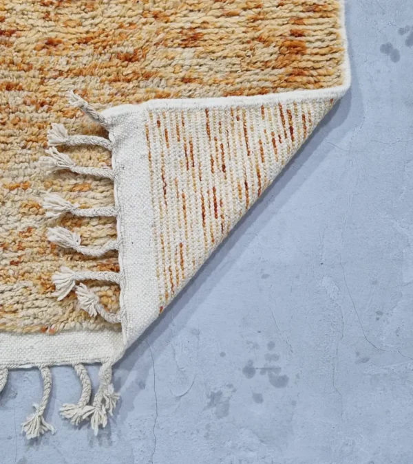 detauled view of Hand-knotted Moroccan wool rug with abstract color-block design in yellow, charcoal, and terracotta on a cream background