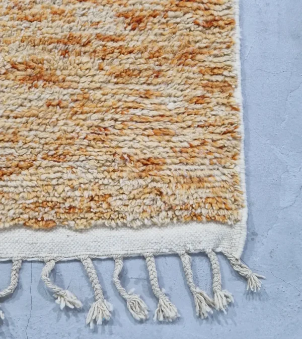 detauled view of Hand-knotted Moroccan wool rug with abstract color-block design in yellow, charcoal, and terracotta on a cream background