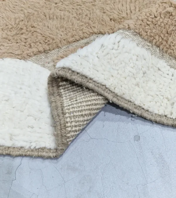 detailed view of Handcrafted Moroccan rug with sculpted high-low abstract neutral design and tassels