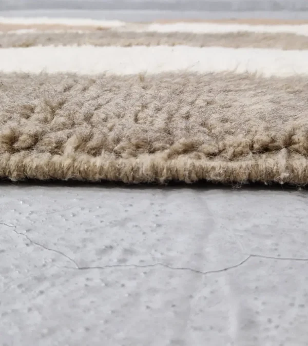 zoomed in view of Handcrafted Moroccan rug with sculpted high-low abstract neutral design and tassels