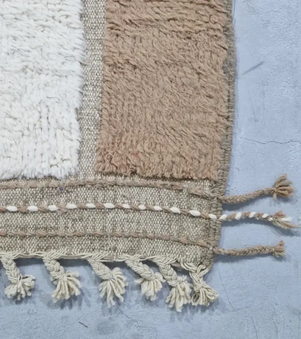 detailed view of Handcrafted Moroccan rug with sculpted high-low abstract neutral design and tassels