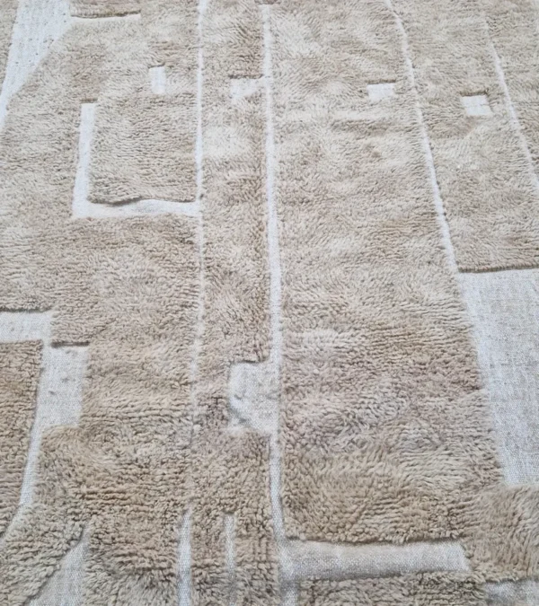 detailed view of Handmade Moroccan wool rug in sandy beige with sculpted off-white linework and tassels