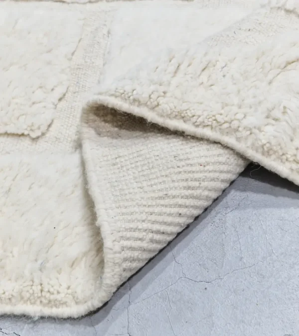 detailed view of Handwoven cream wool rug with sculpted high-low pile geometric pattern