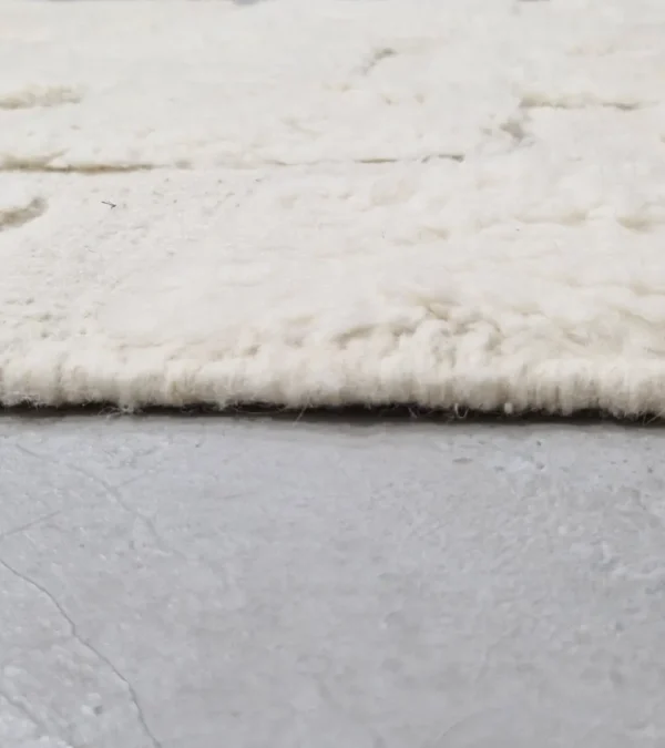 zoomed in view of Handwoven cream wool rug with sculpted high-low pile geometric pattern