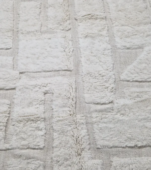 detailed view of Handwoven cream wool rug with sculpted high-low pile geometric pattern