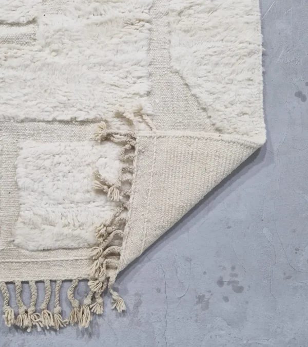 detailed view of Handwoven cream wool rug with sculpted high-low pile geometric pattern