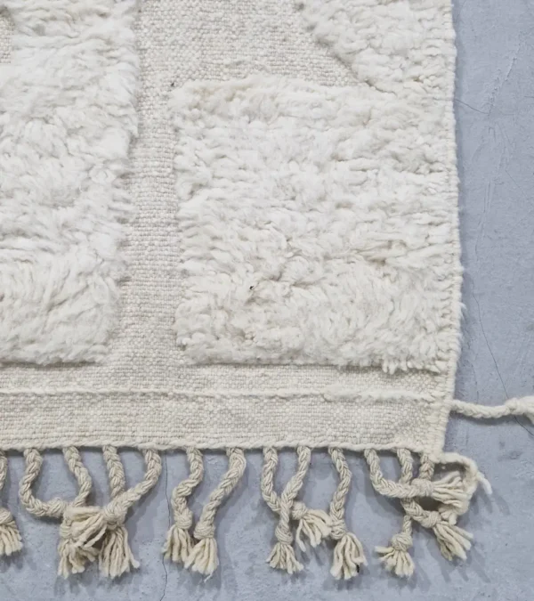 detailed view of Handwoven cream wool rug with sculpted high-low pile geometric pattern