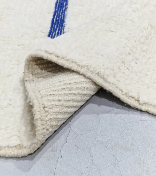 detailed view of Zola handmade Beni Ourain wool rug with a minimalist geometric design of royal blue lines and shapes on an ivory background