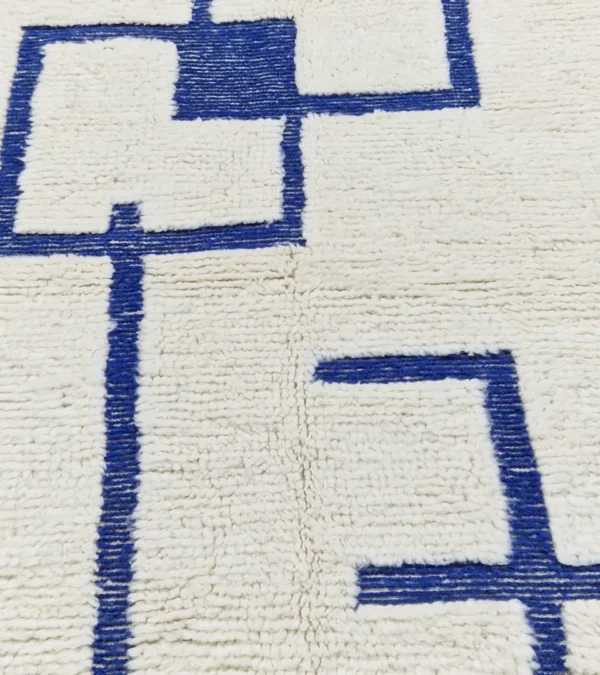 detailed view of Zola handmade Beni Ourain wool rug with a minimalist geometric design of royal blue lines and shapes on an ivory background