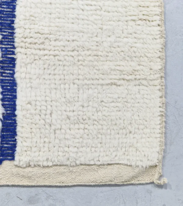 detailed view of Zola handmade Beni Ourain wool rug with a minimalist geometric design of royal blue lines and shapes on an ivory background