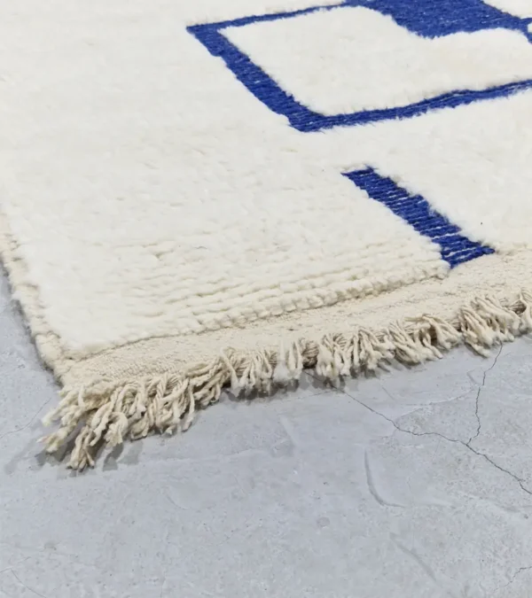 detailed view of Zola handmade Beni Ourain wool rug with a minimalist geometric design of royal blue lines and shapes on an ivory background
