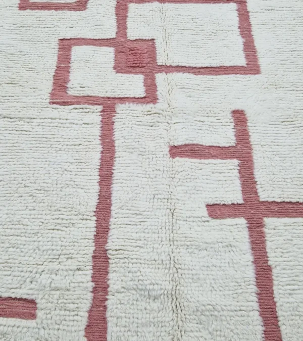 detailed view of Zola handmade Beni Ourain wool rug with a minimalist geometric design of pink lines and shapes on an ivory background